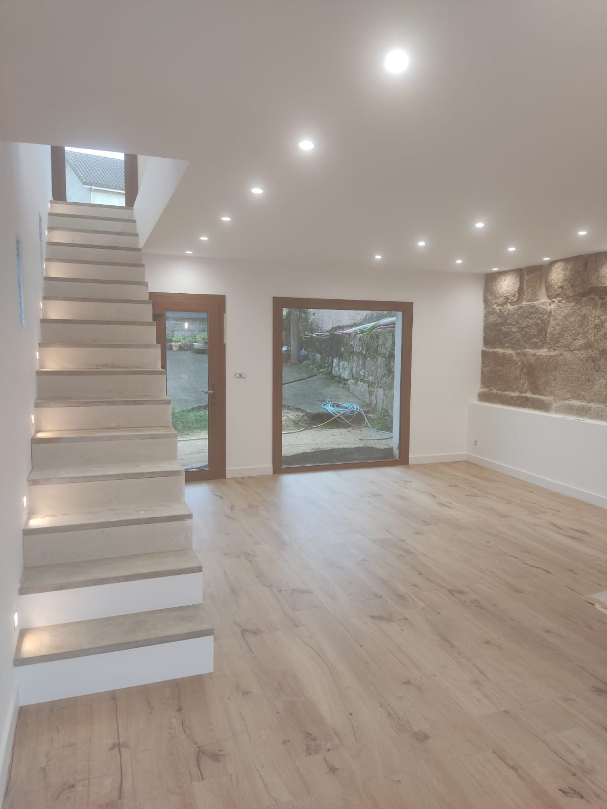 Escalera interior moderna con barandilla de cristal y acabados elegantes tras reforma integral