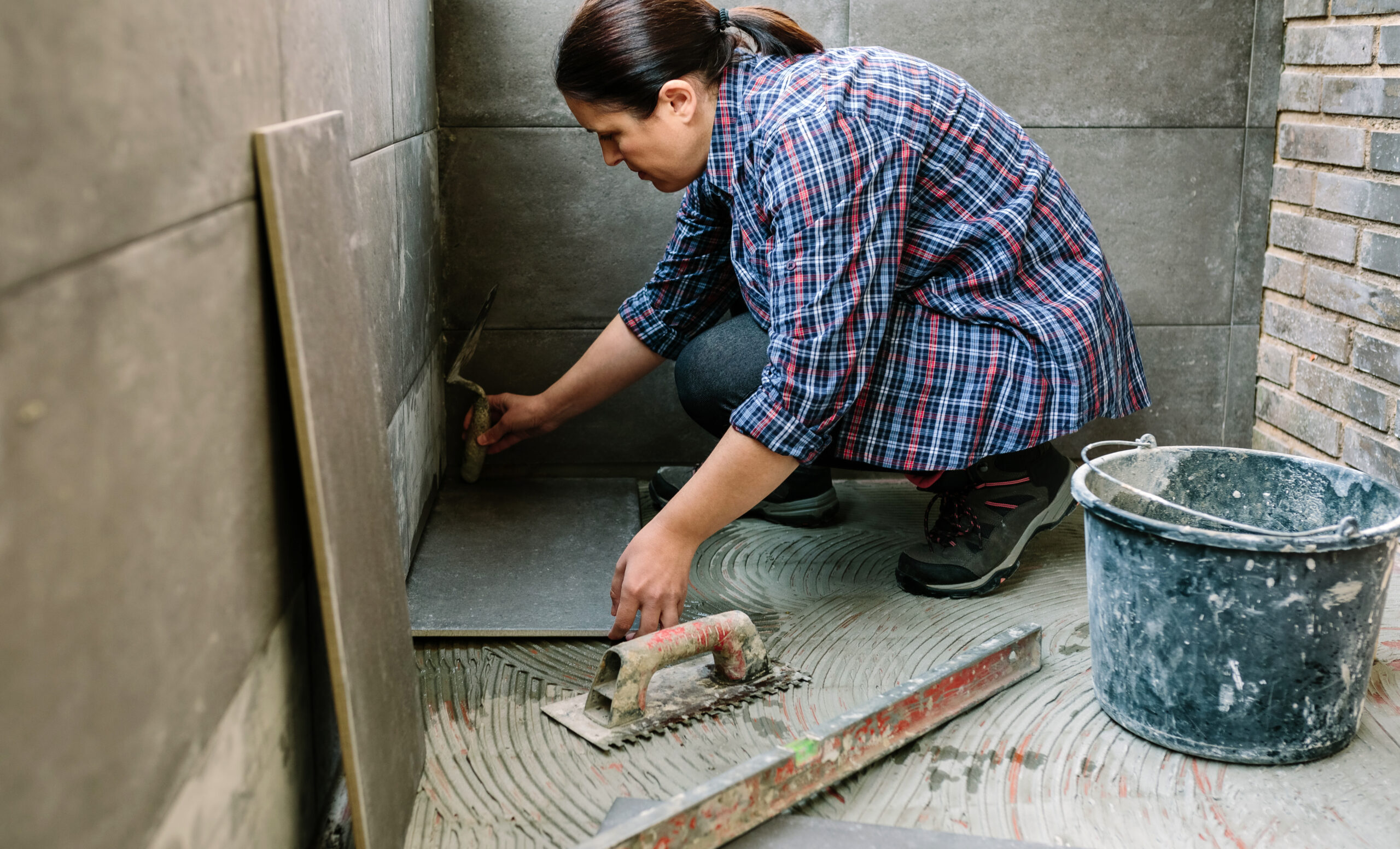 Profesional instalando suelo de ducha con nivel y herramientas especializadas